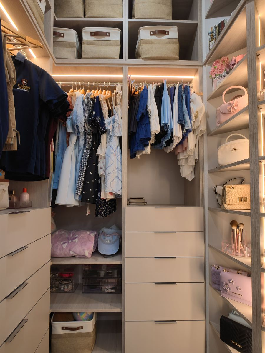 Custom closet corner with drawers, hanging sections, open shelves and labeled storage baskets