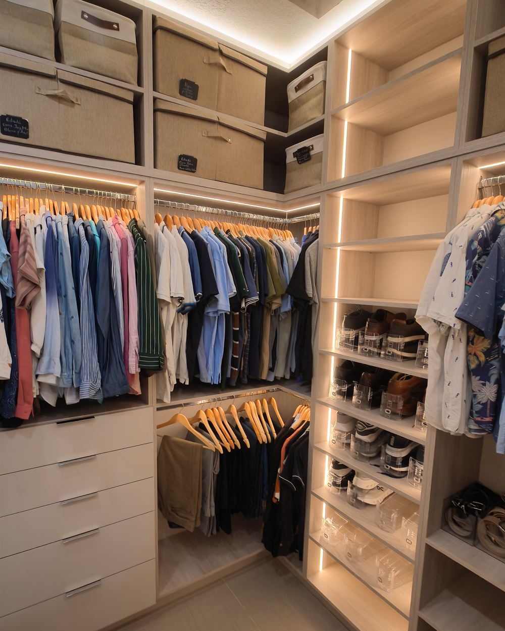 Custom walk-in closet by Dantria Design with LED-lit shelving, double hanging rods, a lit shoe tower and drawers