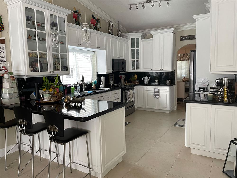 West Kendall kitchen before the remodel with white raised-panel cabinets and black granite countertops