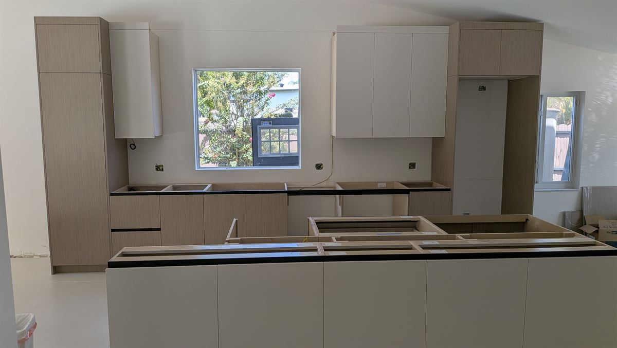 New flat-panel kitchen cabinets and island being installed in a West Kendall kitchen remodel
